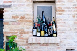 Wine bottles lined up on an exterior windowsill